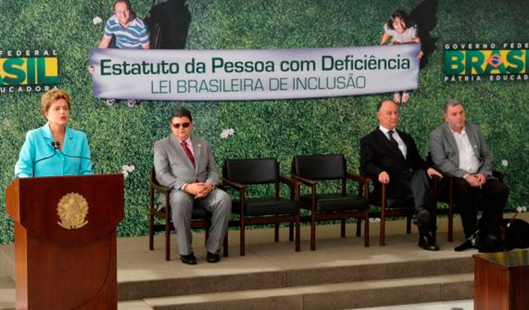 Dilma e mais três homens com uma faixa atrás escrita Estatuto da Pessoa com Deficiência Lei Brasileira de Inclusão