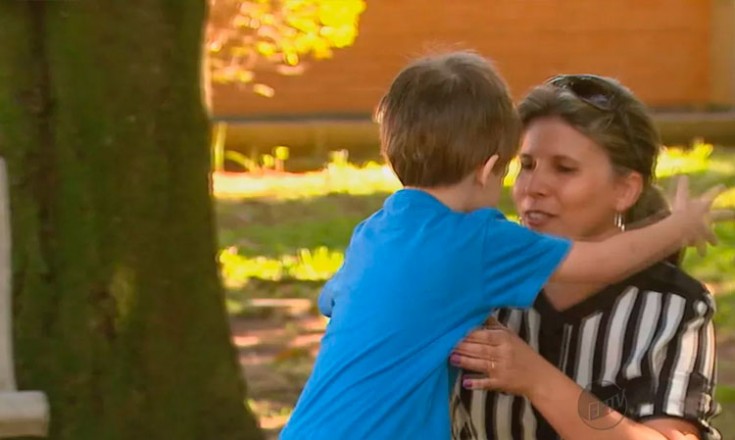 Mulher ajoelhada abraça um garotinho em um parque